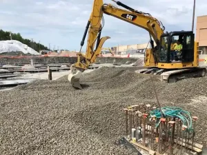 A construction site featuring a bulldozer and a crane, actively engaged in excavation work.